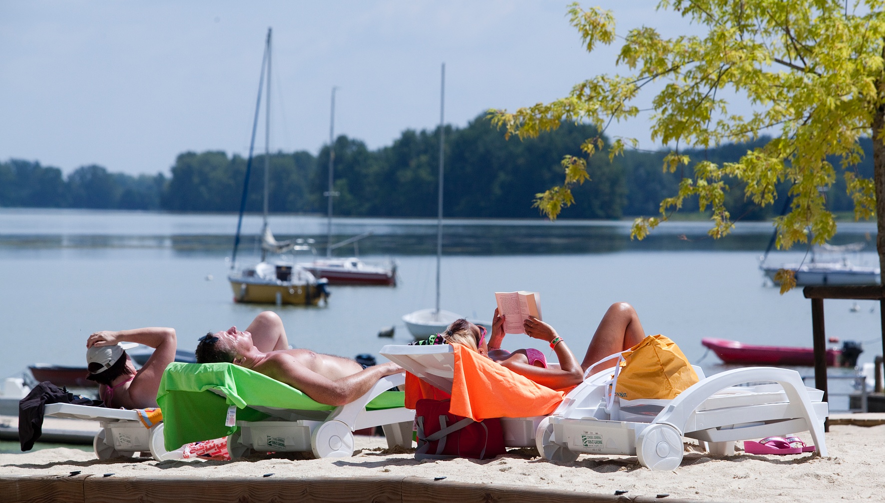 3 personnes entrain de bronzer au soleil face au fleuve de la base de loisirs du Tarn-et-Garonne