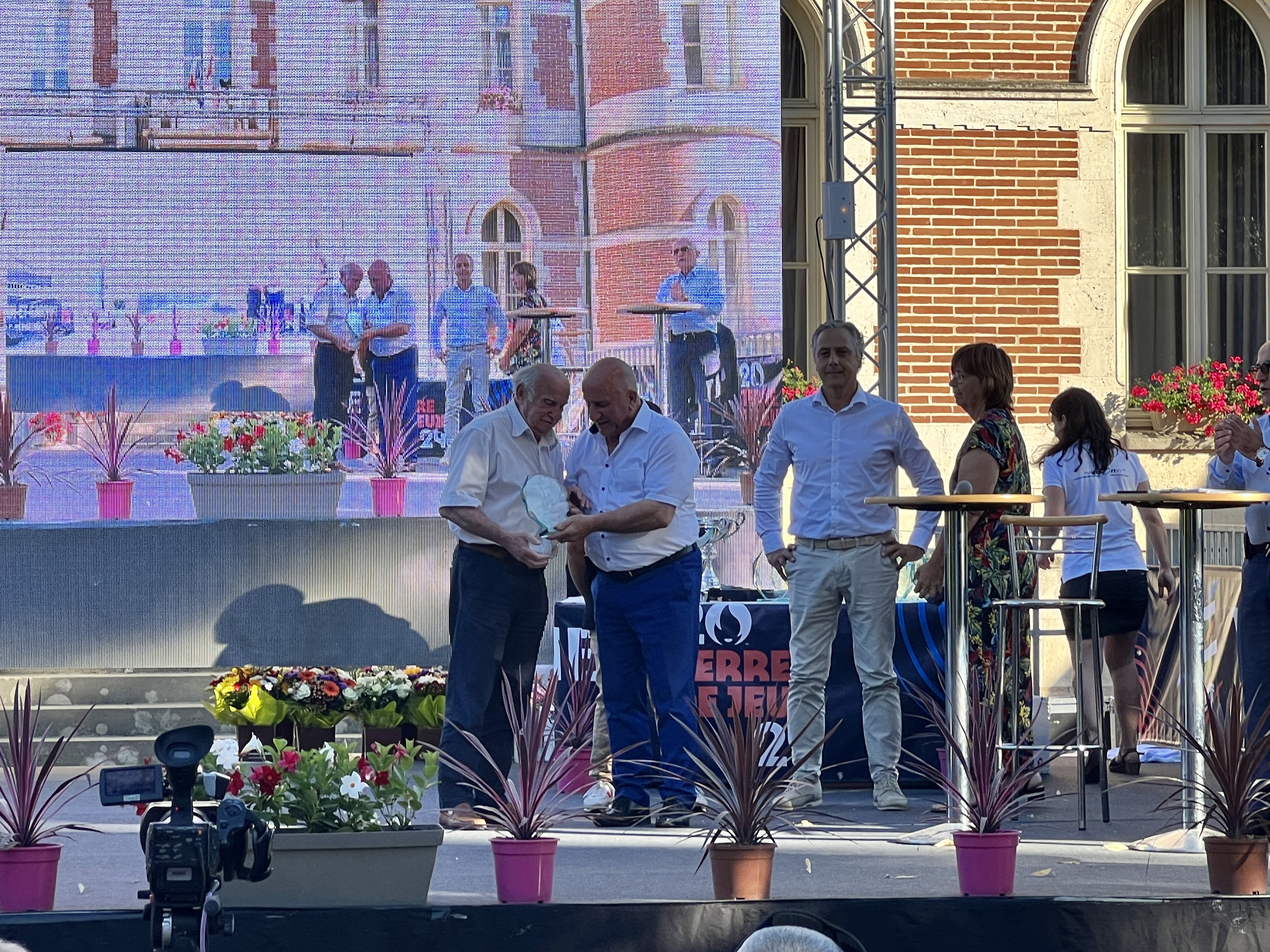 Michel Weill, sur scène, qui remet une coupe à un lauréat en compagnie de Bernard Pécou et Dominique Sardeing 