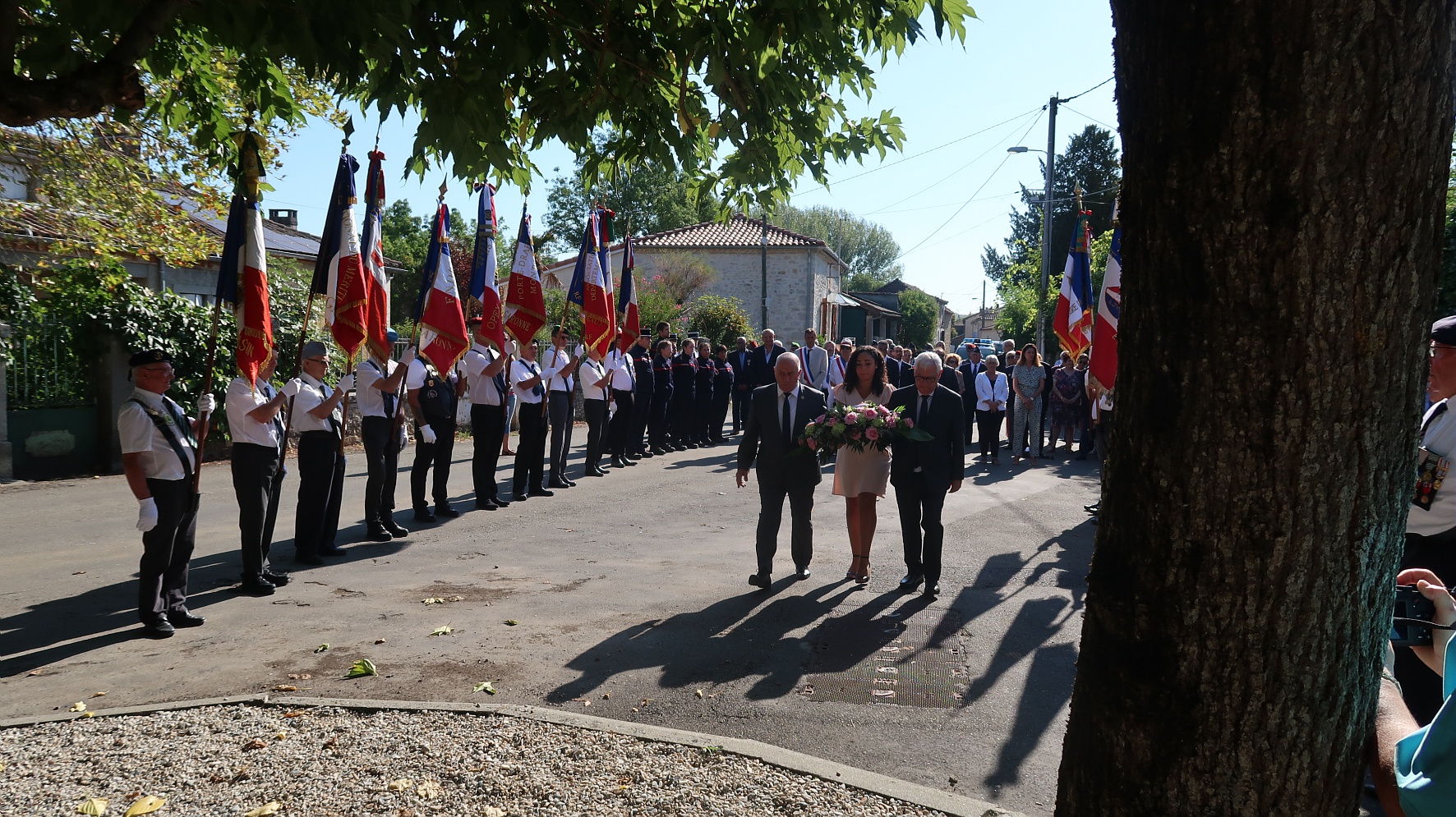 Michel Weill, José Gonzalez et une jeune fille qui vont déposer une gerbe devant le monument aux morts avec, à gauche, les porte-drapeaux.