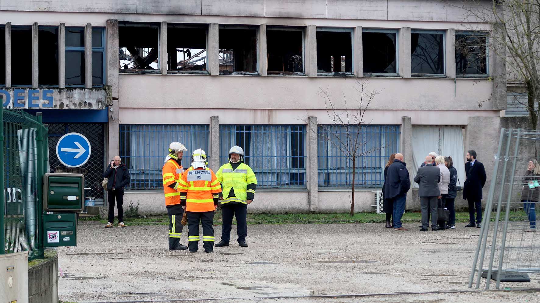 Trois pompiers et les élus devant le bâtiment brûlé IDDEES