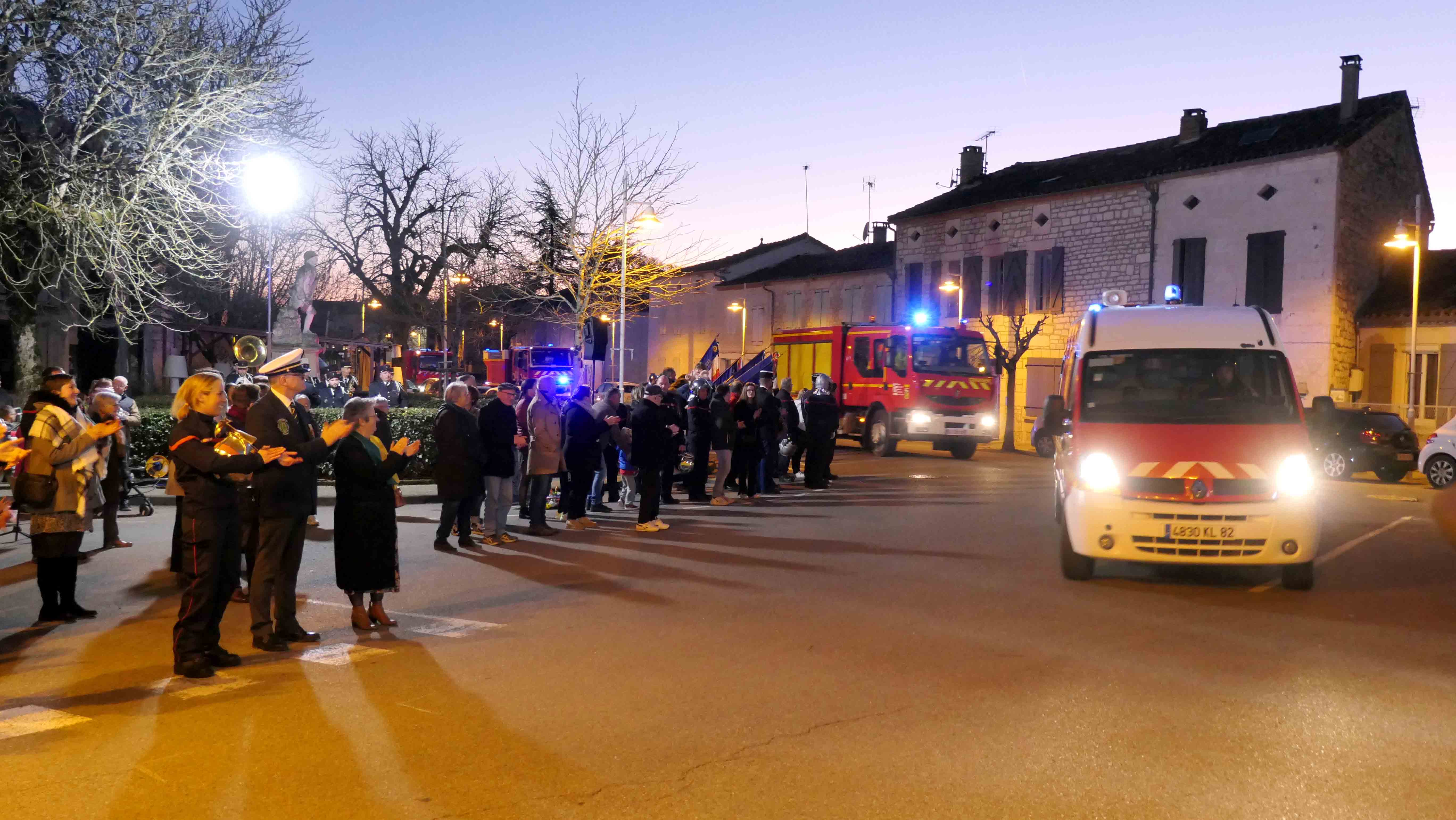 Les véhicules de pompiers qui défilent sur la route applaudie par un grand nombre de personnes 