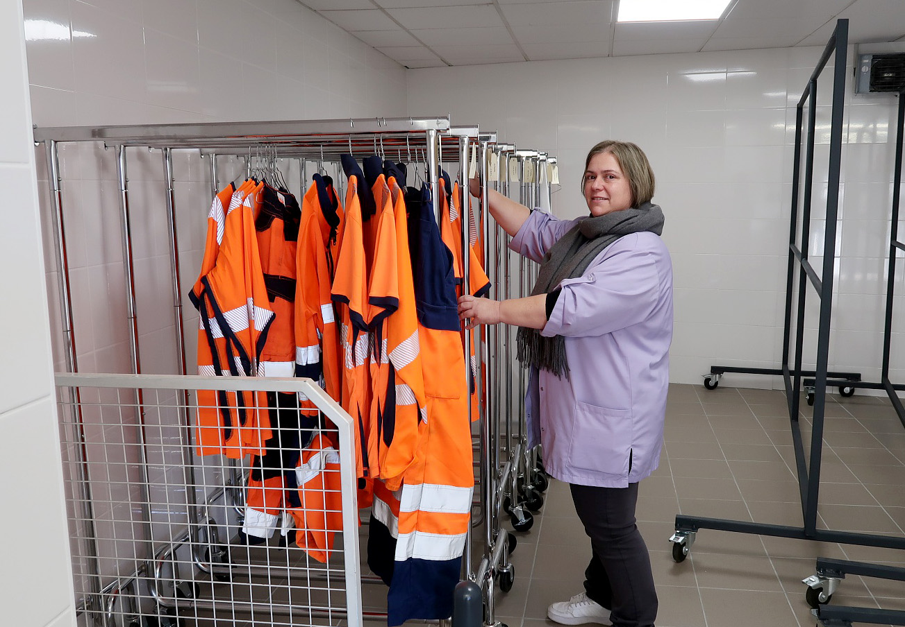 Les vêtements étendus et prêts sur des présentoirs avec la présence d'une employée 