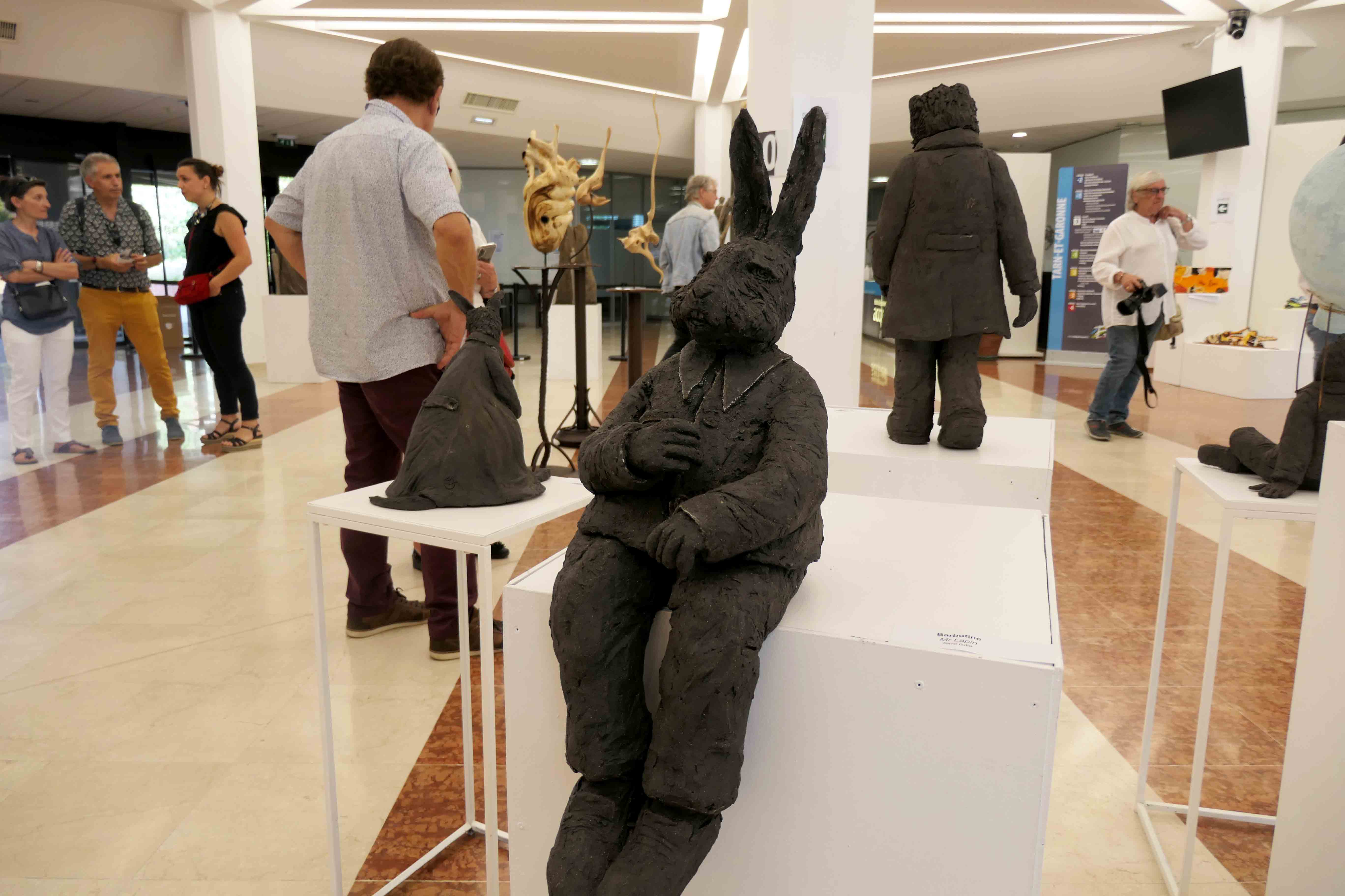 Sculpture en terre noire d'un lapin assis habillé en costume 