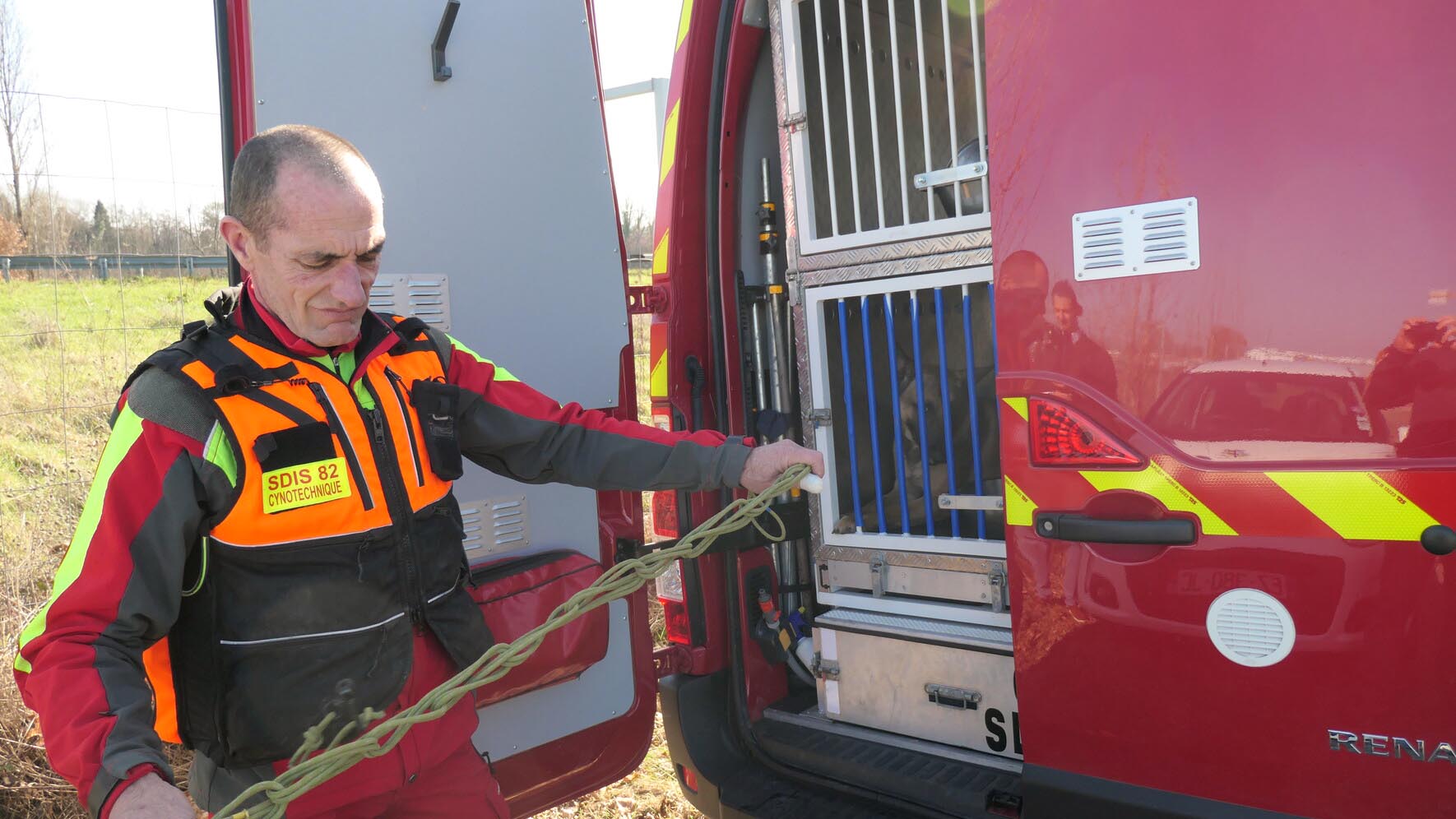 Un maître-chien secouriste à l'arrière d'un camion de pompier destiné au transport de chiens sauveteurs