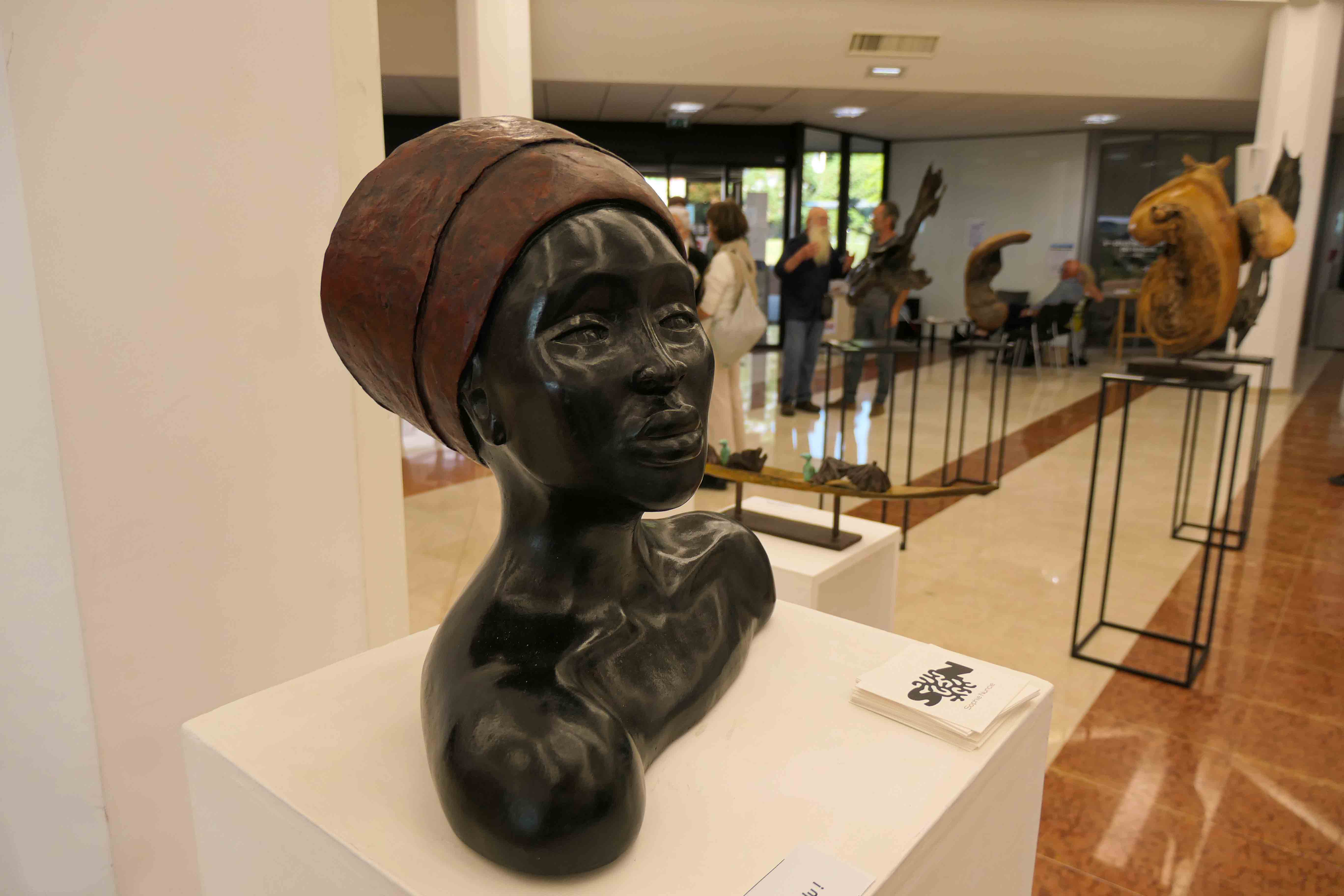 Sculpture d'un buste de couleur sombre d'une femme portant un couvre-chef 