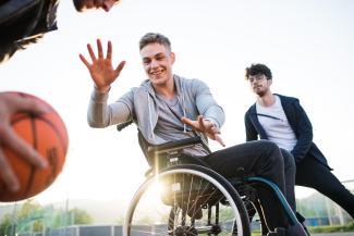 Trois personnes entrain de jouer au basket Deux personnes valides jouant au basket avec une personne en fauteuil roulant