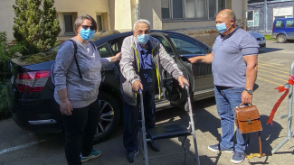 Covid-19 Nous pouvons voir un monsieur assez agés portant un masque du covid-19, en etant accompagné de 2 personnes