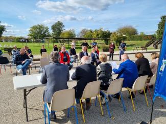 Conférence de presse sur la labellisation « Terre de jeux 2024 » attribuée à à la base de loisirs du Tarn et de la Garonne à Saint-Nicolas-de-la-Grave Les élus, le président et d'autres personnalités de dos assis à table devant un petit public assis également à la base de loisirs du 82