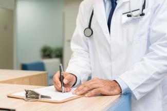 Image représentant l'hôpital Un médecin en train d'écrire sur une feuille
