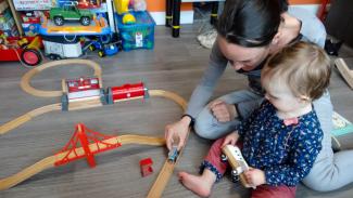 Une femme et un enfant jouant joyeusement avec un circuit de train en bois