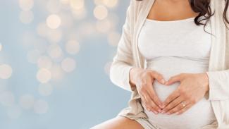 Une femme enceinte qui fait un coeur avec ses mains sur son ventre 