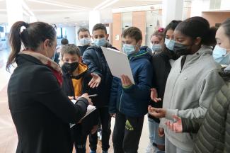 Un groupe de collégiens en train de récupérer des plaquettes pour écrire dessus à une dame 