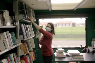 Étape : rangement de livres dans le bibliobus Un agent du département en train de ranger des livres sur des des étagères dans le bibliobus
