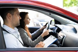 Un nouveau fonds d’aide aux jeunes pour le passage du permis de conduire Un moniteur d'auto-école dans une voiture avec une conductrice