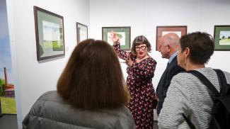 Inauguration de l’exposition « Avec plaisir ! Carnet de voyage insolite de Tarn-et-Garonne » à l'espace des Augustins Cendrine Bonami-Redler en train d'expliquer son exposition au président et au public présent sur place