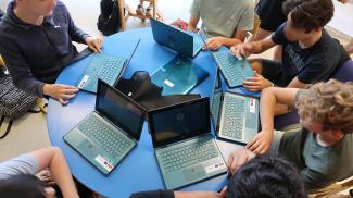 Ordinateurs portables au service de la pédagogie Plusieurs jeunes avec leur ordinateur portable sur un table ronde