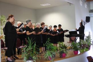 La chorale dirigée par Jérémy Vinkhe Une chorale composée majoritairement de femmes sur scène avec le chef d'orchestre qui lève la main en l'air