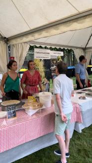 Stand de crêpes à la fête de la musique 2022 Deux jeunes femmes en train de réaliser des crêpes sur un stand et un monsieur qui passe commande
