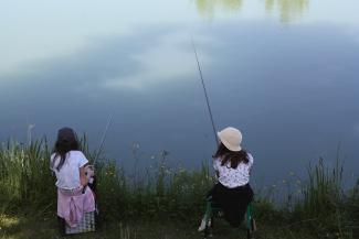 Apprentissage de la pêche grâce à la FDAAPPMA Deux jeunes filles à la pêche au bord d'un lac