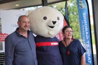 Michel Weill remet les premières peluches Pompy aux sapeurs-pompiers du département Nadine Sinopoli et Emmanuel Cros qui posent avec la mascotte Pompy des sapeurs-pompiers