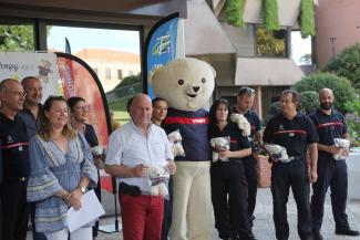 Michel Weill remet les premières peluches Pompy aux sapeurs-pompiers du département Michel Weill en compagnie de plusieurs élus et sapeurs-pompiers du Département qui posent avec la mascotte Pompy