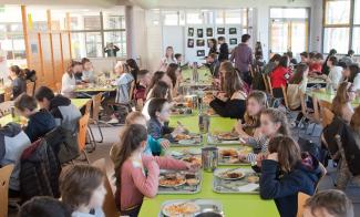 Photo du self du collège Vercingétorix Des enfants en train de manger au self avec leur plateau à table