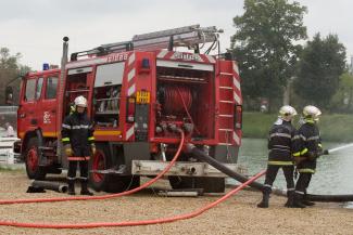 Photo des pompiers en exercice Trois pompiers en train d'utiliser leur lance d'eau lors d'un exercice