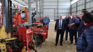 Michel Weill qui visite une exploitation agricole et ses engins avec des membres de la CUMA