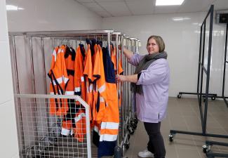 Les vêtements étendus et prêts sur des présentoirs avec la présence d'une employée 