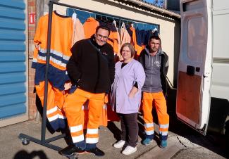Trois employés qui posent devant un présentoir des vêtements de travail 