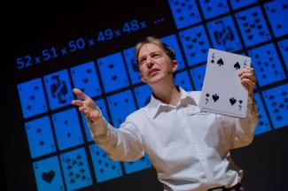 Manu Houdart dans Very Math Trip Manu Houdart dans Very Math Trip tenant une carte à jouer à la main