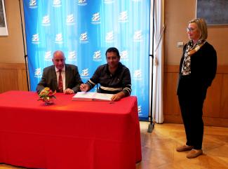 Signature du contrat d'équipement pour 6 communes Michel Weill assis à table avec le représentant d'une des 6 communes lors de la signature du contrat d'équipements