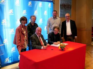 Signature du contrat d'équipement pour 6 communes Michel Weill assis à table avec les représentants d'une des 6 communes lors de la signature du contrat d'équipements