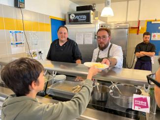 L’opération Restau’collège Un cuisinier qui sert une assiette à un enfant