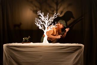 Pièce de théâtre "Quand les corbeaux auront des dents" à l'espace des Augustins le 29 mars 2024 Un homme de profil tenant un fusil dans les mains et qui se cache derrière un arbre blanc