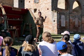 un acteur en costume médiéval devant un public d'enfants