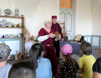 Le Moyen-Âge expliqué aux enfants par une femme et un homme déguisés avec des habits de l'époque du Moyen-Âge