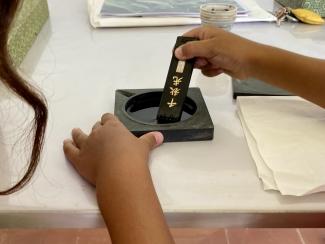 Activité : "Les mardis des tout-petits" à l'abbaye de Belleperche Un enfant en train de tremper un calligraphe dans de l'encre noire