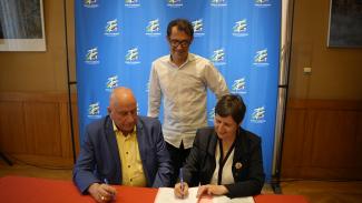 Signature du contrat d'équipement pour le village de Montricoux Trois élus assis à table en train de signer un contrat dont 1 debout