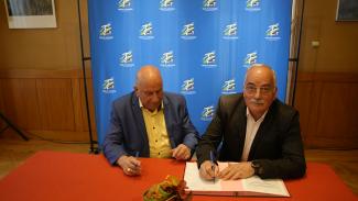 Signature du contrat d'équipement pour le village de Saint-Cirq Deux élus assis à table en train de signer un contrat