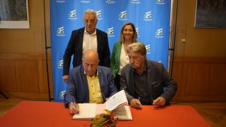Signature du contrat d'équipement pour le village de Serignac Quatre élus dont 2 debout et 2 assis à table entrain de signer un contrat