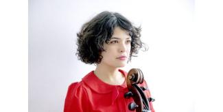 Spectacle de Ana Carla Maza musicienne et chanteuse à l'espace des Augustins Buste d'une jeune femme regardant au loin avec un violoncelle contre elle