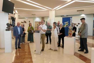 Plusieurs personnes debout derrière un homme qui fait un discours devant un pupitre 