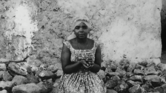 Projection du film documentaire "CESARIA ÉVORA, LA DIVA AUX PIEDS NUS" à l'espace des Augustins Femme de couleur de peau métisse assis sur des pierres. La photo est en noir et blanc