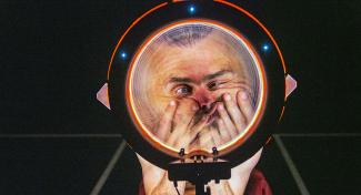 Image d'une tête d'humain réalisant une grimace à travers une loupe géante.