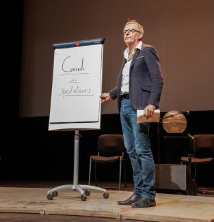 Conseils aux spectateurs Un homme se tient sur scène avec un tableau